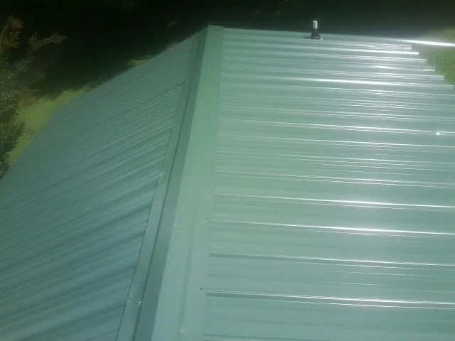 New green metal panels meeting at the ridge of a roof — Flat Roof Repair work by our crew in Shelbyville